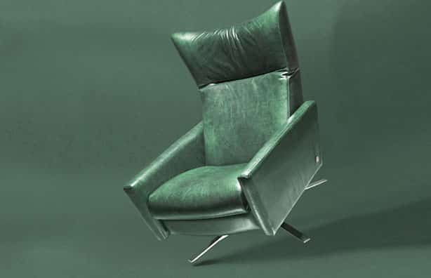 Emerald green leather couch tilted against dark green background