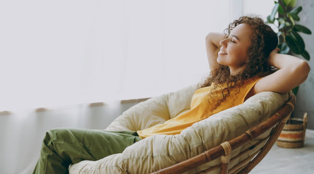 Smiling woman relaxes in modern wood & cushioned chair from San Francisco Design